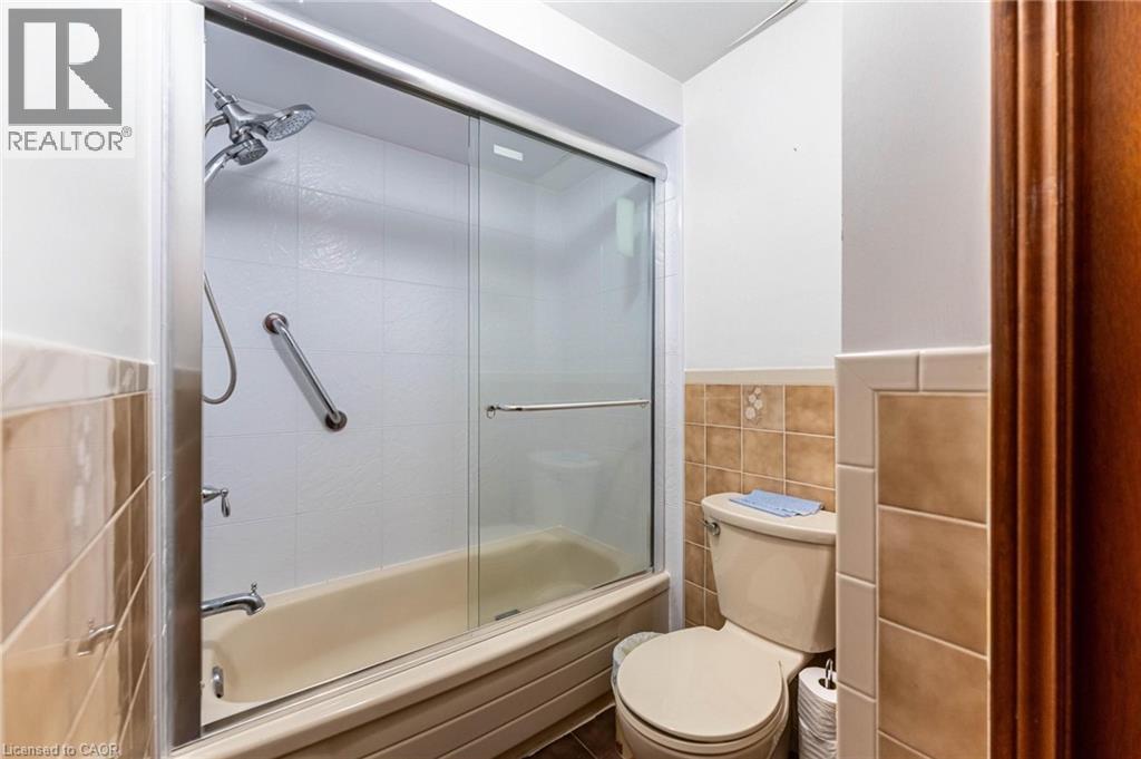 Full bathroom featuring combined bath / shower with glass door, tile walls, and wainscoting - 5 Charing Drive, Hamilton, ON - Indoor Photo Showing Bathroom
