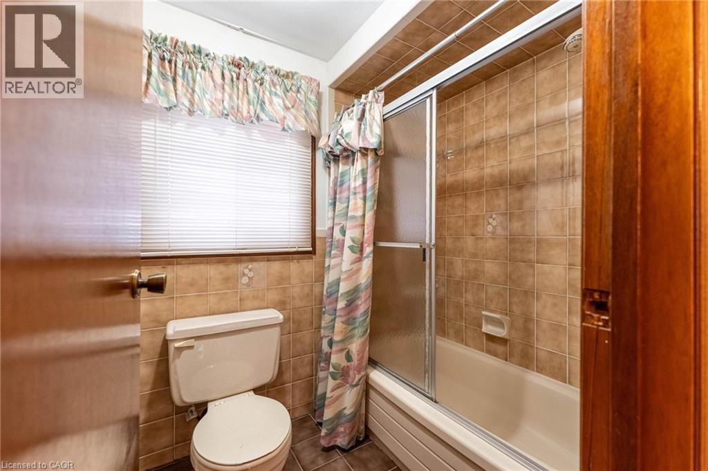 Full bathroom featuring bath / shower combo with glass door, tile walls, and tile patterned flooring - 5 Charing Drive, Hamilton, ON - Indoor Photo Showing Bathroom