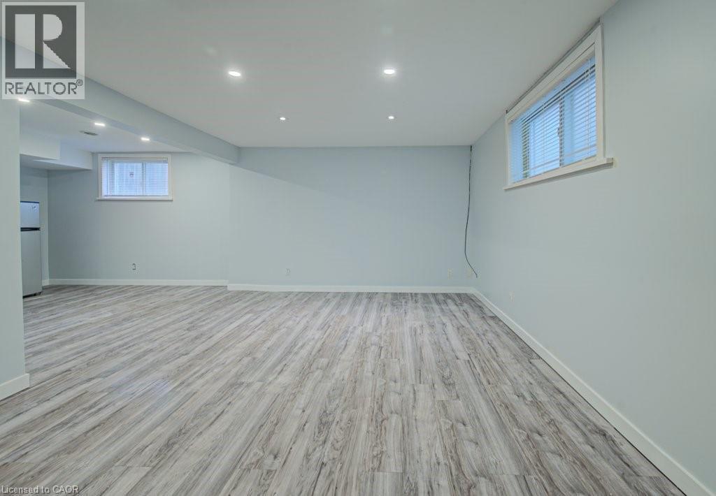 Basement with recessed lighting, light wood-style flooring, and freestanding refrigerator - 310 Magnolia Drive, Hamilton, ON