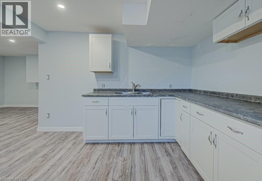 Kitchen with light wood-type flooring, white cabinets, dark countertops, and recessed lighting - 310 Magnolia Drive, Hamilton, ON