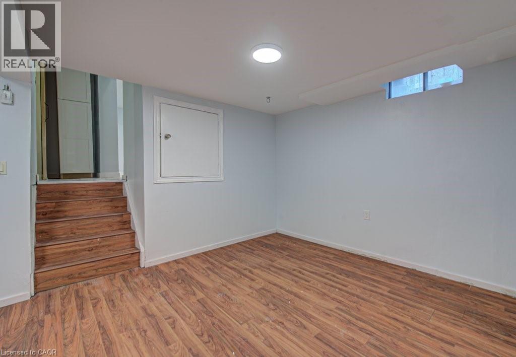 Empty room with wood finished floors and stairway - 310 Magnolia Drive, Hamilton, ON