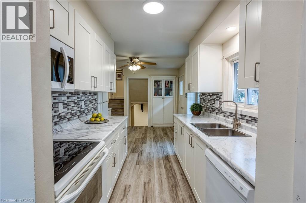 Kitchen featuring white appliances, white cabinets, light wood-style floors, and a ceiling fan - 310 Magnolia Drive, Hamilton, ON - Indoor Photo Showing Kitchen With Double Sink With Upgraded Kitchen