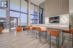 Indoor wet bar with a high ceiling, floor to ceiling windows, and light stone countertops -