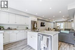Kitchen with stainless steel appliances, open floor plan, white cabinetry, light wood-style floors, and recessed lighting -