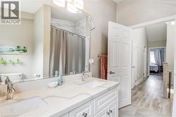 Bathroom featuring a shower with curtain, double vanity, ensuite bath, and light wood-type flooring -