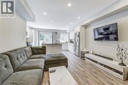 Living area with light wood-type flooring and recessed lighting -
