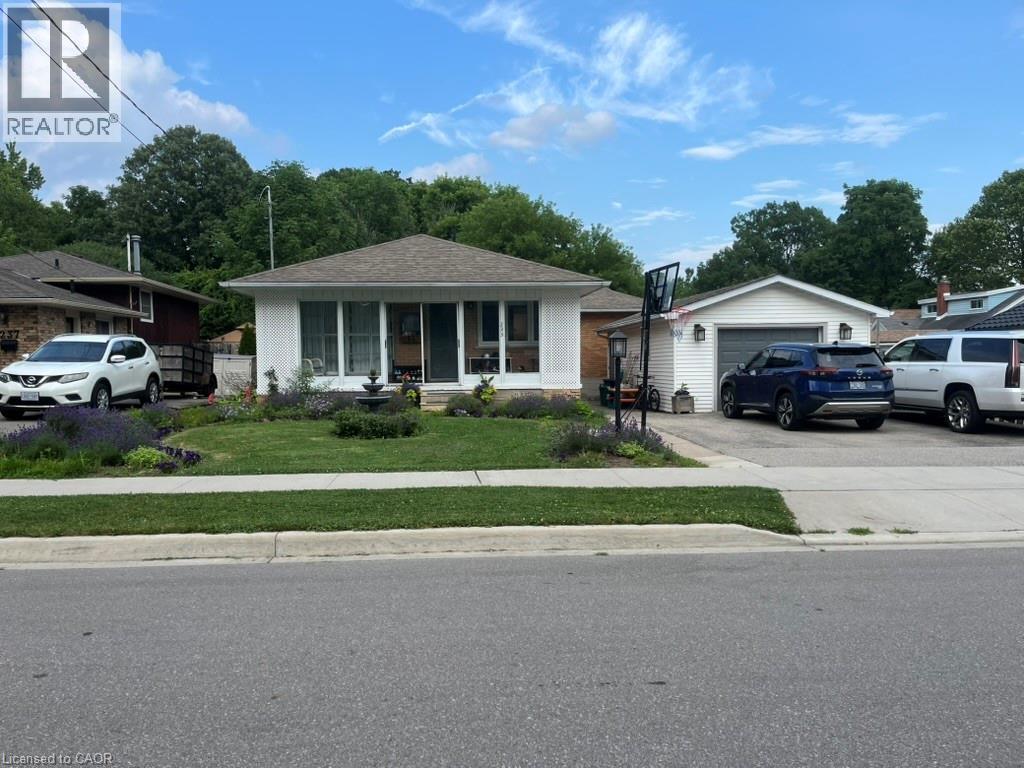 Bungalow-style home featuring a garage, an outbuilding, a front lawn, roof with shingles, and driveway - 235 Fearnwood Street, Cambridge, ON - Outdoor