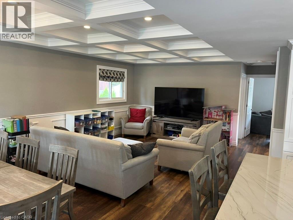 Living room featuring coffered ceiling, beam ceiling, dark wood-type flooring, wainscoting, and crown molding - 235 Fearnwood Street, Cambridge, ON - Indoor