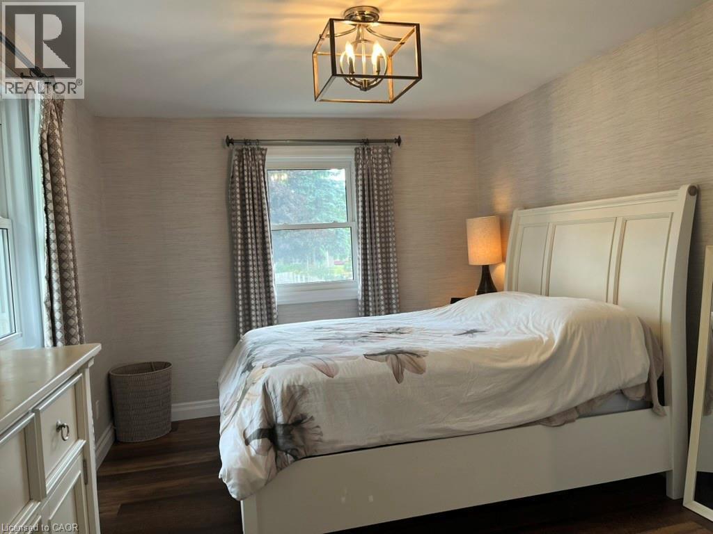 Bedroom featuring wallpapered walls, dark wood-style floors, and a chandelier - 235 Fearnwood Street, Cambridge, ON - Indoor Photo Showing Bedroom