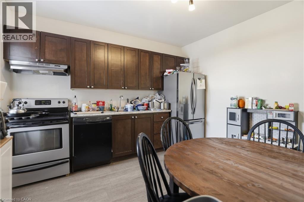 Kitchen featuring stainless steel appliances, dark wood finish cabinets, light countertops, and light wood-style floors - 260 Prospect Street S, Hamilton, ON - Indoor Photo Showing Kitchen
