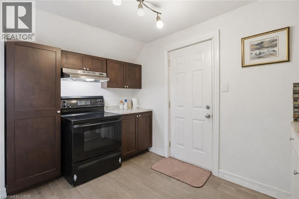 Kitchen with electric range, dark wood finish cabinetry, lofted ceiling, and light wood finished floors - 260 Prospect Street S, Hamilton, ON - Indoor Photo Showing Kitchen