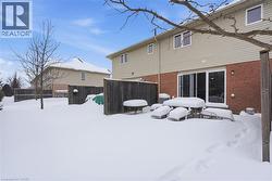 Snow covered back of property featuring brick siding -