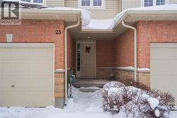 Snow covered property entrance with a garage and brick siding -