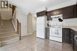 Kitchen with white appliances, light countertops, dark brown cabinetry, under cabinet range hood, and decorative backsplash -
