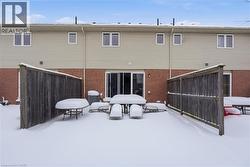 Snow covered property with outdoor dining space and brick siding -