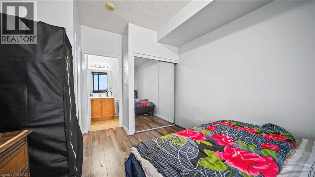 Bedroom with dark wood-style floors, a textured ceiling, and a closet - 388 Prince Of Wales Drive Unit# 1609, Mississauga, ON - Indoor Photo Showing Bedroom