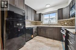 Kitchen featuring black appliances, dark wood finish cabinetry, light countertops, and tasteful backsplash -