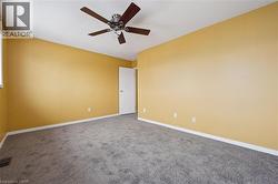 Carpeted empty room featuring baseboards and a ceiling fan -