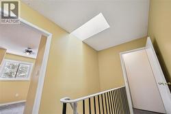 Hallway with a skylight, carpet flooring, a textured ceiling, and an upstairs landing -