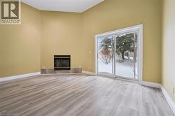 Unfurnished living room with a high ceiling, a tiled fireplace, and light wood-type flooring -