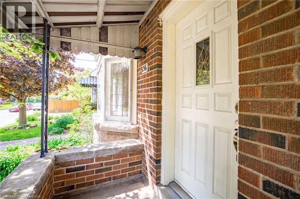 View of exterior entry featuring a porch and brick siding - 136 Glen Road, Hamilton, ON - Outdoor With Exterior