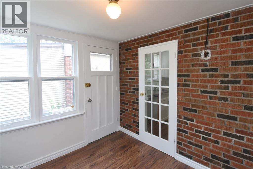 Doorway with brick wall and wood finished floors - 136 Glen Road, Hamilton, ON - Indoor Photo Showing Other Room