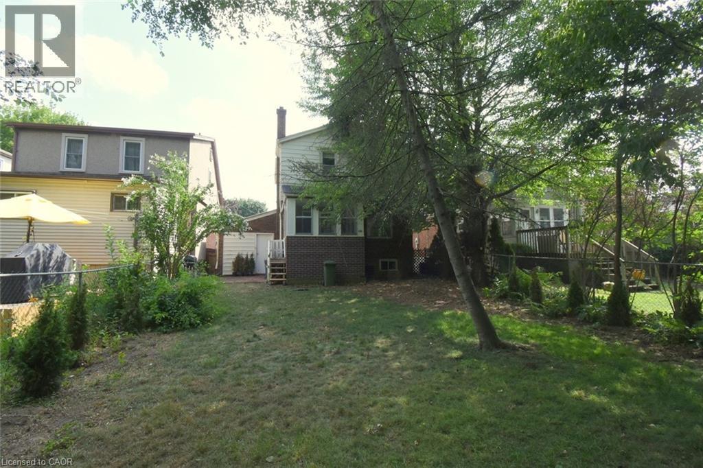 Rear view of property featuring a fenced backyard, a wooden deck, and brick siding - 136 Glen Road, Hamilton, ON - Outdoor