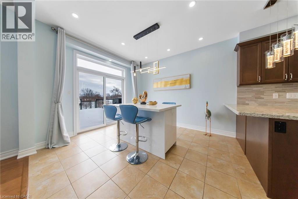 Kitchen featuring a breakfast bar area, decorative light fixtures, decorative backsplash, light stone counters, and dark wood finish cabinetry - 59 Greti Drive, Hamilton, ON - Indoor