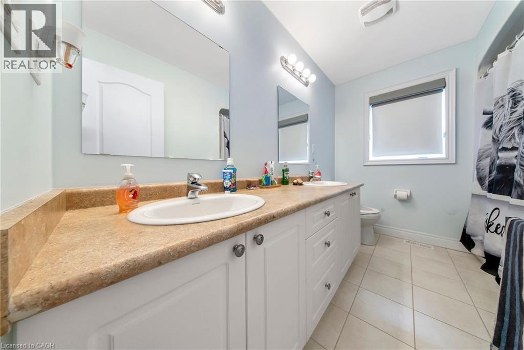 Bathroom with double vanity, a shower with shower curtain, and light tile patterned flooring - 59 Greti Drive, Hamilton, ON - Indoor Photo Showing Bathroom