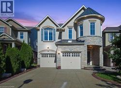 View of front of property with a standing seam roof, a metal roof, stone siding, stucco siding, and concrete driveway -