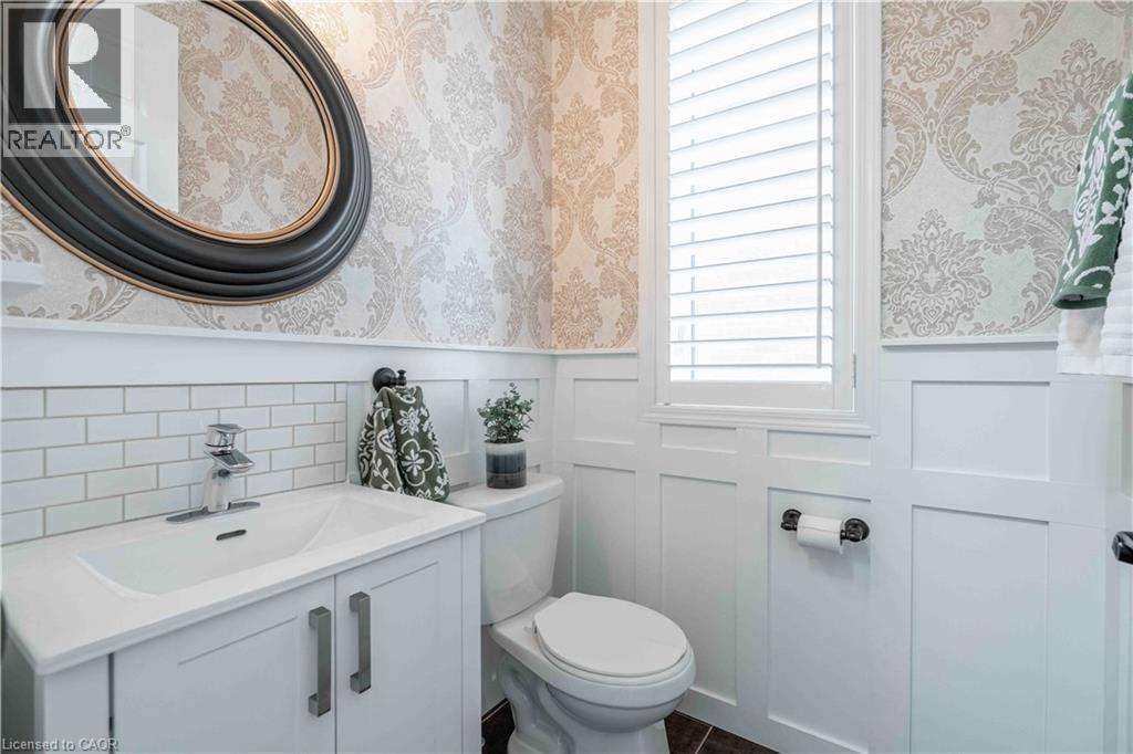 2-pc powder room featuring wallpapered walls, a wainscoted wall, vanity, and a decorative wall. - 115 Larry Crescent, Caledonia, ON - Indoor Photo Showing Bathroom