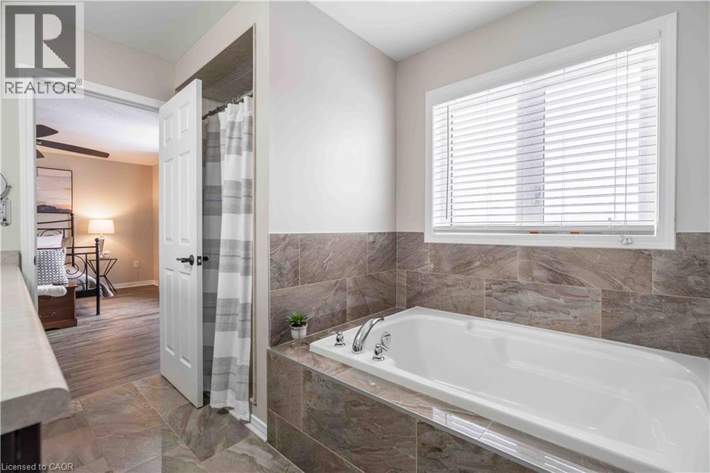 Full bath with a garden tub, a shower with curtain, and marble finish floors - 115 Larry Crescent, Caledonia, ON - Indoor Photo Showing Bathroom