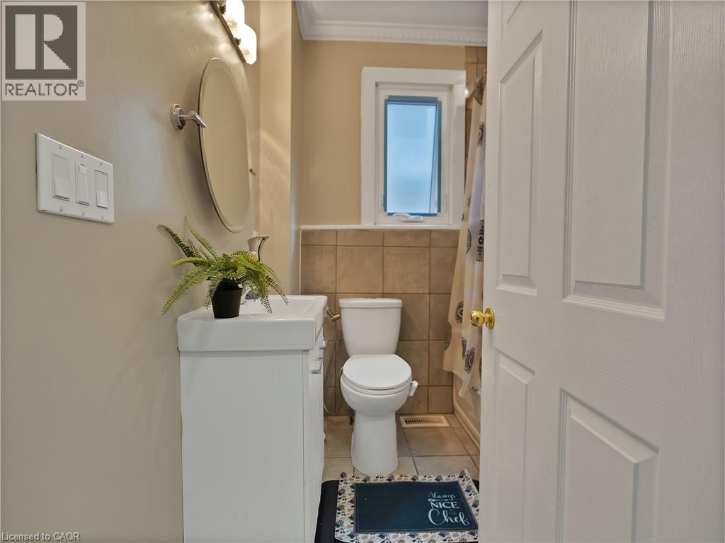 Bathroom featuring tile patterned floors, vanity, tile walls, and crown molding - 210 East 24Th Street, Hamilton, ON - Indoor Photo Showing Bathroom