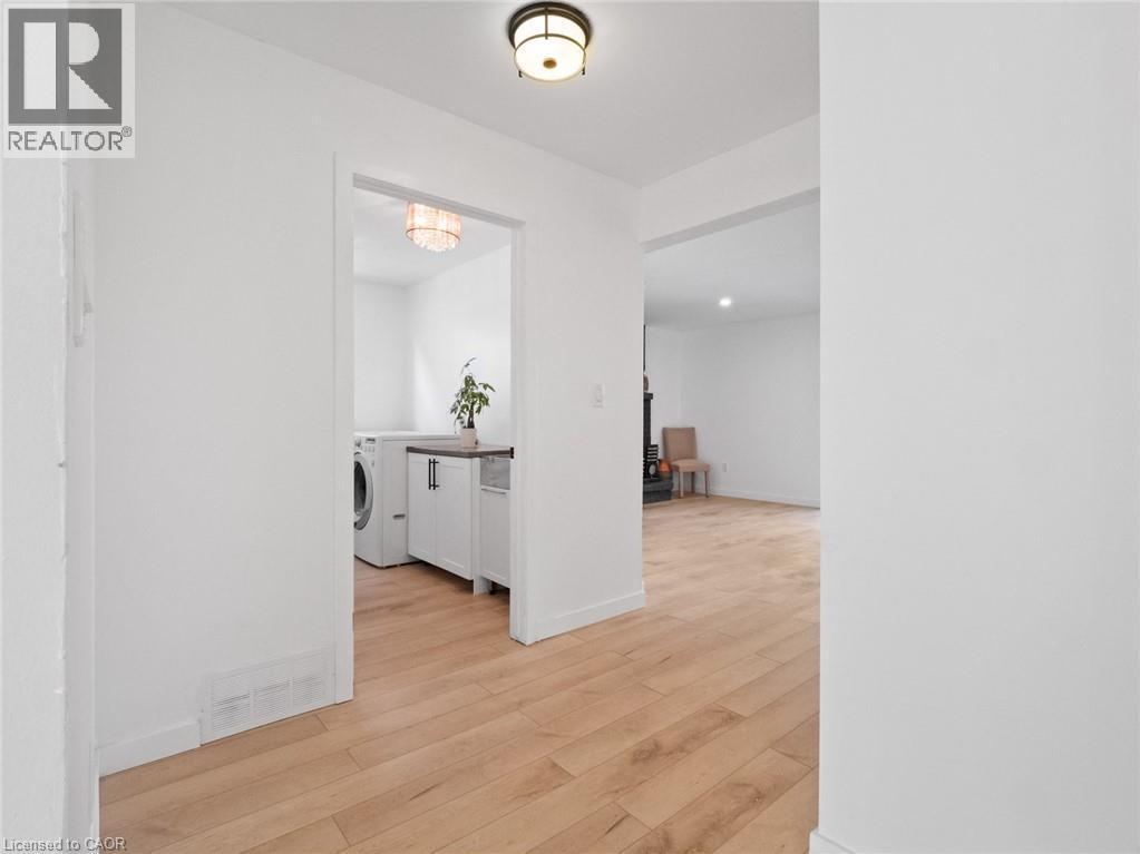 Hallway featuring light wood-style flooring, washer / dryer, baseboards, and visible vents - 24 Keefer Road, Thorold, ON - Indoor