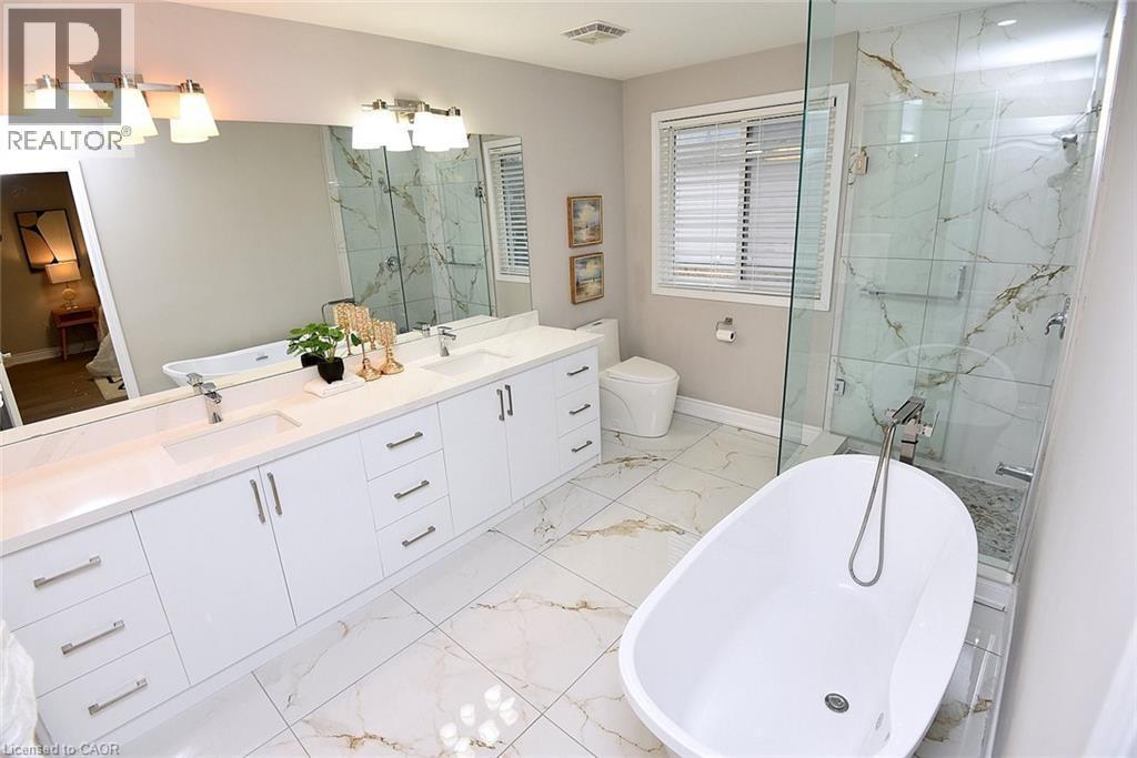 Bathroom featuring a freestanding bath, a marble finish shower, double vanity, and light marble finish flooring - 5109 Blue Spruce Avenue, Burlington, ON - Indoor Photo Showing Bathroom