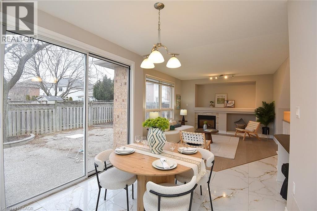 Dining area featuring a fireplace, light marble finish flooring, and a chandelier - 5109 Blue Spruce Avenue, Burlington, ON - Indoor Photo Showing Dining Room With Fireplace