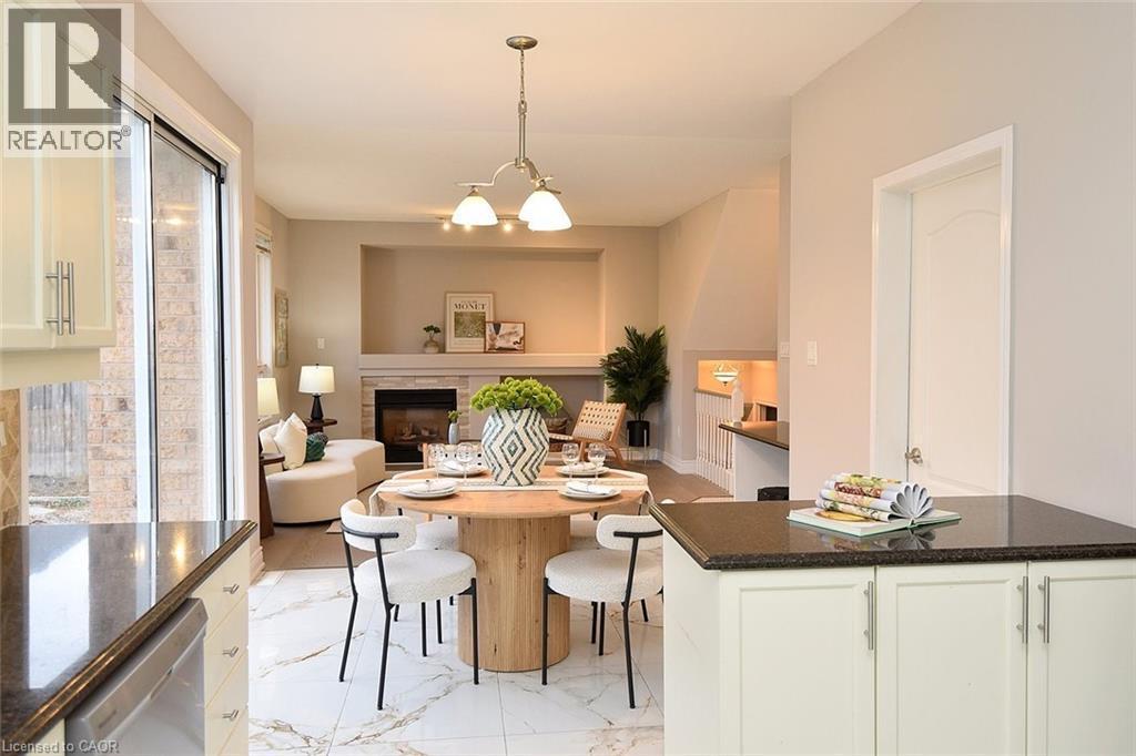 Dining room with a glass covered fireplace, hanging lights, and light marble finish floors - 5109 Blue Spruce Avenue, Burlington, ON - Indoor Photo Showing Dining Room