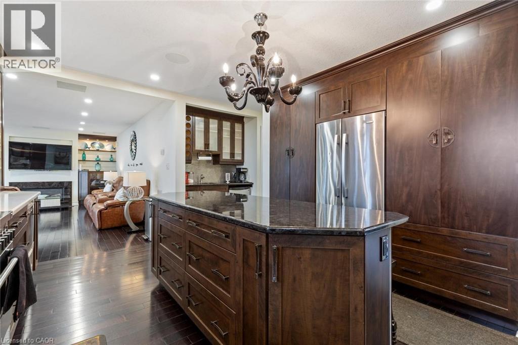 Kitchen featuring tasteful backsplash, dark brown cabinets, dark wood-type flooring, built in refrigerator, and a kitchen island - 1073 North Service Road, Hamilton, ON - Indoor Photo Showing Kitchen With Upgraded Kitchen
