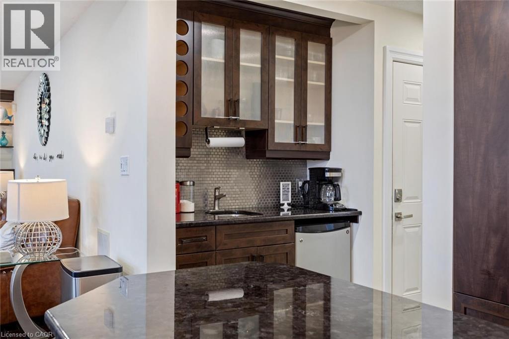 Kitchen with dark stone counters, sink, tasteful backsplash, dark brown cabinetry, and stainless steel refrigerator - 1073 North Service Road, Hamilton, ON - Indoor Photo Showing Kitchen
