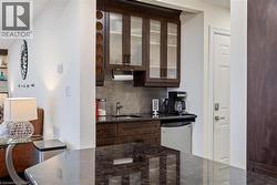 Kitchen with dark stone counters, sink, tasteful backsplash, dark brown cabinetry, and stainless steel refrigerator -