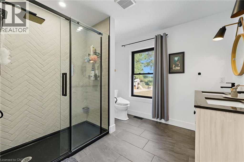 Full bathroom featuring a stall shower, double vanity, and dark tile patterned flooring - 115 Lakeshore Road, Port Burwell, ON - Indoor Photo Showing Bathroom