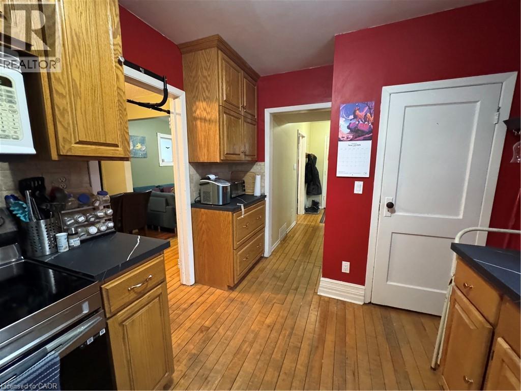 The kitchen features natural wood cabinetry, a double gooseneck sink framed by a wide window view, and access to the semi-refinished mudroom. Appliances included: fridge, stove, range hood, microwave, - 344 Paisley Road, Guelph, ON - Indoor Photo Showing Kitchen