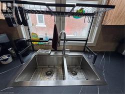 The kitchen features natural wood cabinetry, a double gooseneck sink framed by a wide window view, and access to the semi-refinished mudroom. Appliances included: fridge, stove, range hood, microwave, -