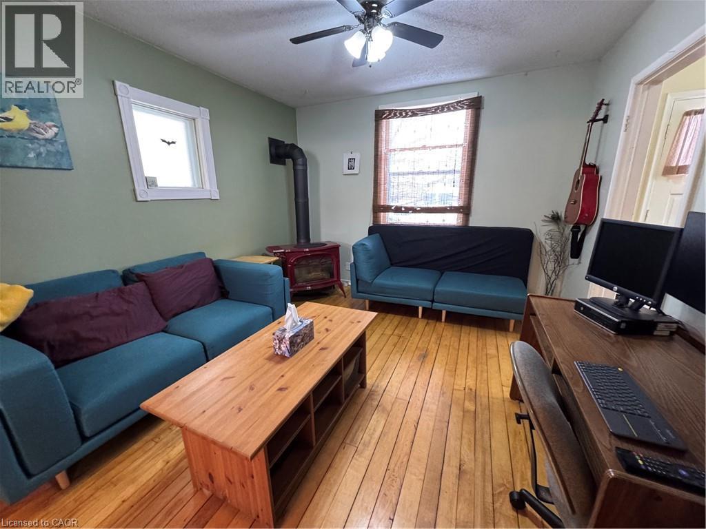 comfortable living room, warmed by a red gas stove and ceiling fan - 344 Paisley Road, Guelph, ON - Indoor Photo Showing Living Room