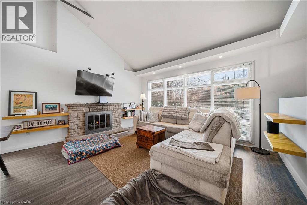 Living room with a stone fireplace, dark wood finished floors, high vaulted ceiling, and recessed lighting - 276 Lakeshore Road W, Oakville, ON - Indoor Photo Showing Living Room With Fireplace