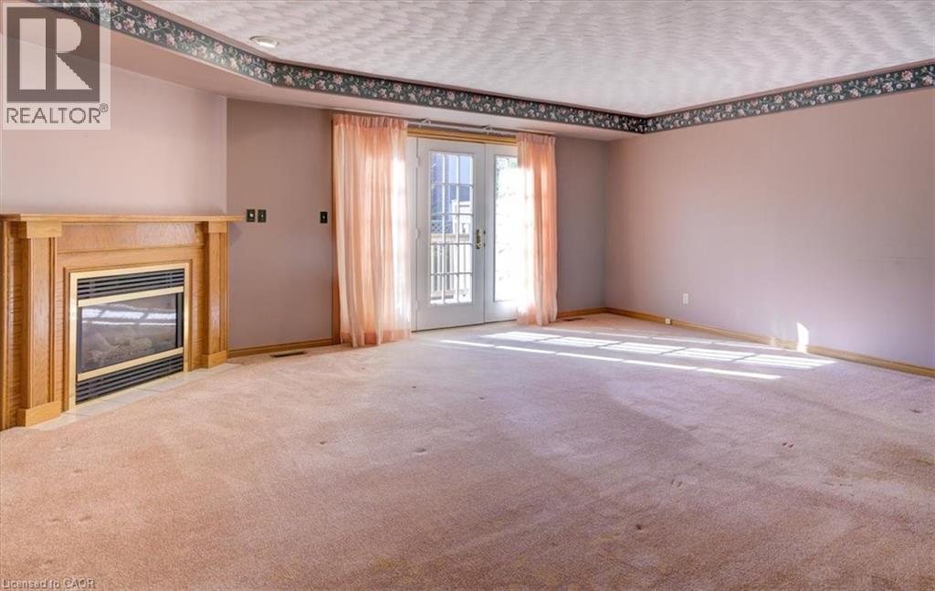 Enjoy a seamless indoor-outdoor flow with triple garden doors that fill the room with sunshine and greenery. - 42 Donly Drive S Unit# 2, Simcoe, ON - Indoor With Fireplace