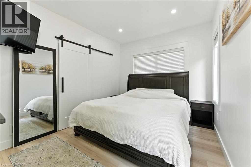 Bedroom with a barn door, recessed lighting, and light wood finished floors - 9 Macneil Court, Port Burwell, ON - Indoor Photo Showing Bedroom