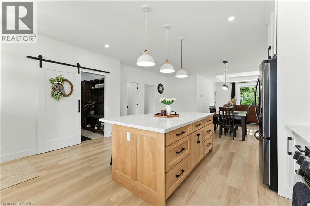 Kitchen featuring a barn door, a center island, light brown cabinets, hanging light fixtures, and light stone countertops - 9 Macneil Court, Port Burwell, ON - Indoor Photo Showing Kitchen With Upgraded Kitchen