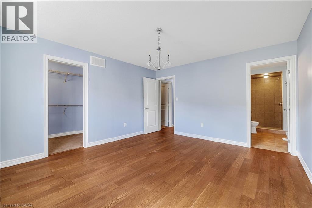 Unfurnished bedroom with a walk in closet, wood finished floors, and ensuite bath - 89 Sonoma Valley Crescent, Hamilton, ON - Indoor Photo Showing Other Room
