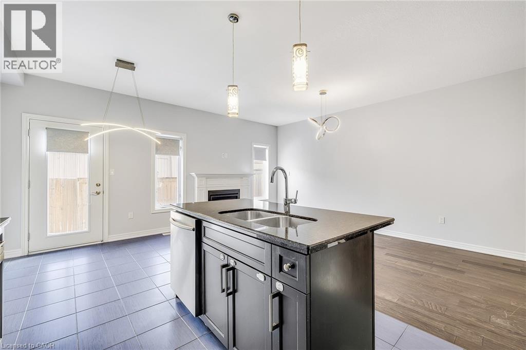 Kitchen featuring open floor plan, an island with sink, hanging light fixtures, dishwasher, and dark stone countertops - 89 Sonoma Valley Crescent, Hamilton, ON - Indoor Photo Showing Kitchen With Double Sink
